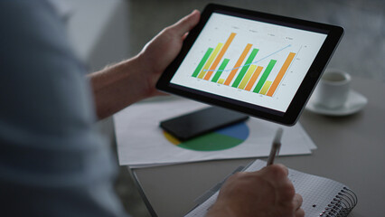 Business man researching charts graph using tablet computer pad in remote office