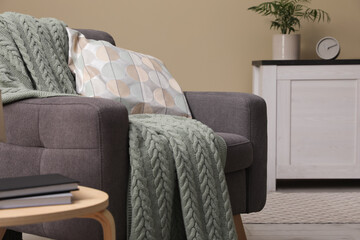 Living room interior with comfortable grey armchair, pillow and plaid