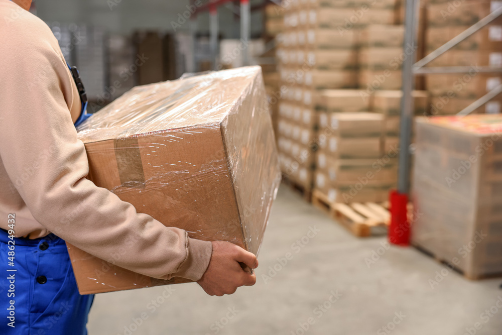 Poster Worker with cardboard box in warehouse, closeup. Wholesaling