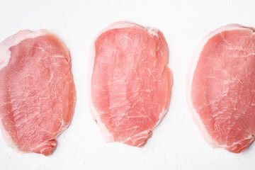 Raw organic meat. Pork steaks, fillets for grilling, baking or frying, on white stone table background, top view flat lay