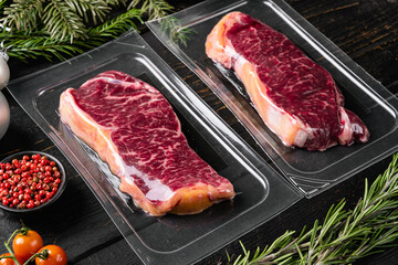 Fresh raw red meat vacuum sealed in plastic, on black wooden table background