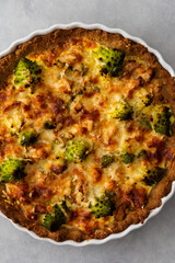 Homemade baked pot pie with Romanesco cabbage, chicken breast and cheese in a round ceramic baking dish on a gray background, top view