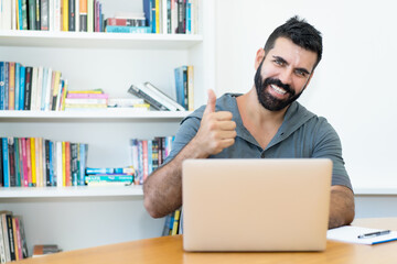 Motivated latin american teacher with hipster beard at computer