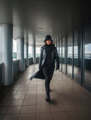 Stylish girl in black coat on roof of business center in form of an agent and spy