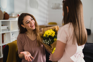 daughter giving a flowers to her mother at home
