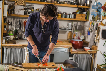 man cutting red paprika in kitchen