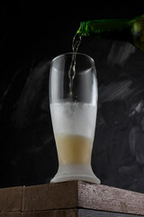 Beer pouring into cup in a bar. Wooden desk and grey background