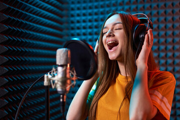 Teen girl in recording studio with mic over acoustic absorber panel background