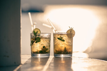 Two mojito cocktails against the sunset light on the beach
