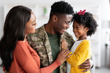 Happy Black Soldier Man Embracing With Wife And Little Daughter At Home