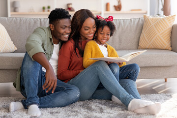 Cheerful African American Family With Little Daughter Reading Book Together At Home