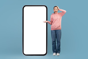 Amazed korean millennial woman posing with big smartphone