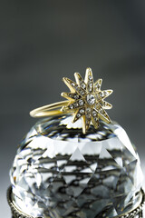 gold ring in the form of a multi-beam star with diamonds lies on a polyhedral crystal, dark background, close-up