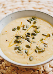 Celeriac cream soup with pumpkin seeds and oil on jute matt