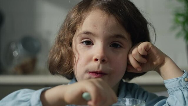 Beautiful baby girl eating healthy food in the kitchen in the morning. Happy childhood happy child eating.