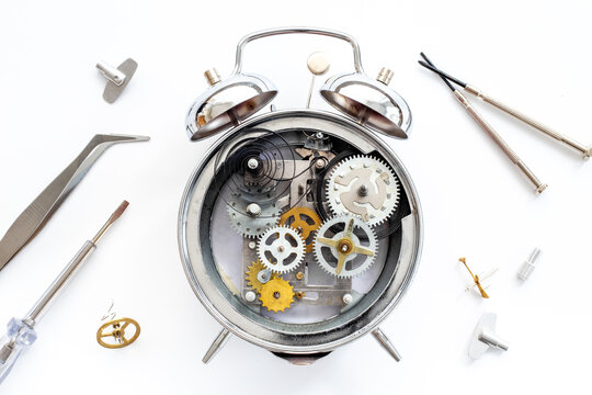 Watch mechanism and watchmaker tools near open alarm clock