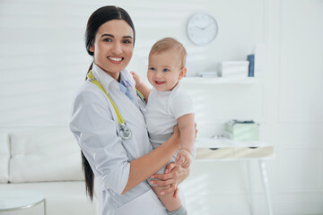 Young pediatrician with cute little baby in clinic. Space for text