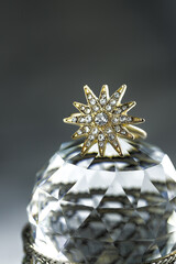 gold ring in the form of a multi-beam star with diamonds lies on a polyhedral crystal, dark background, close-up