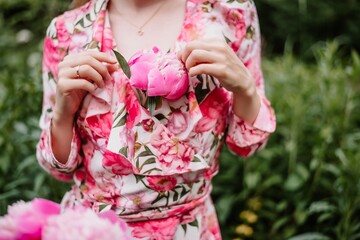 Obraz premium a peony girl has a peony between her breasts in a dress with peonies in summer.