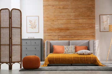 Room interior with sofa unfolded into bed near wooden wall
