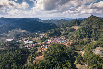 Fototapeta na wymiar Aerial view of local village in the valley among tropical rainforest at countryside