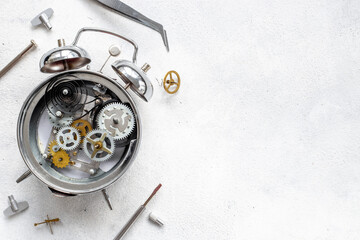 Watchmaker tools near watch mechanism of alarm clock