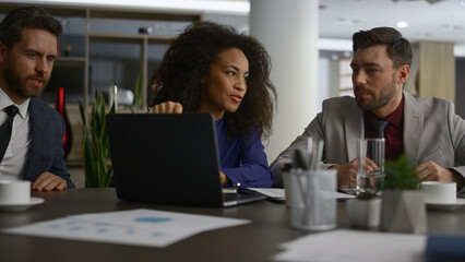 Fototapeta na wymiar Multiracial coworkers talking finance using laptop in modern company office.