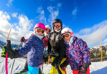 Family enjoying winter vacations taking selfie in skiing gear.