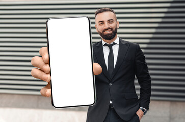 Smiling Male Entrepreneur In Suit Holding Big Smartphone With Blank White Screen