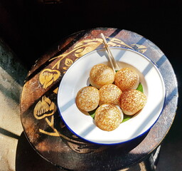 Khanom Krok is placed in a white plate with a pointed stick placed on the side for dipping (like a fork) and placed on a chair by the window to get sunlight. Khanom Krok (Thai dessert) is commonly eat - obrazy, fototapety, plakaty