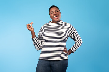 Happy Plump Black Lady Snapping Fingers Standing Over Blue Background