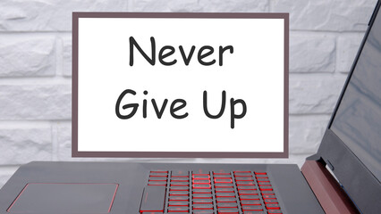 Never give up a phrase written on a magnetic board next to a laptop with a glowing keyboard