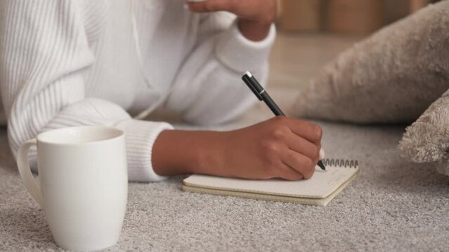 To do list. Journal planning. Author creativity. Unrecognizable woman hand writing goal achievement notes in diary studying at home enjoying weekend rest leisure on floor.