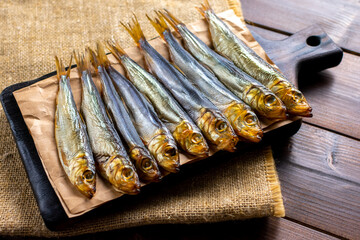 Smoked fish on a wooden cutting board on a dark wooden table. Close up.