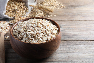 Bowl with raw oatmeal on wooden table. Space for text