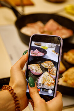 Photographing food on a mobile phone. Smartphone taking pictures of the chicken in a frying pan.