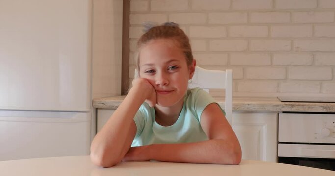 the girl sits in the kitchen and smiles. child is happy at home