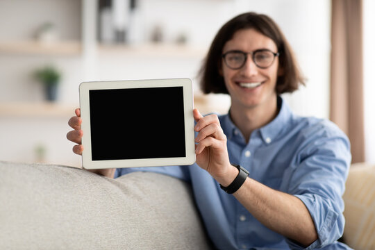 Mockup image of happy guy showing digital tablet with blank screen for app, website design or advertisement, free space