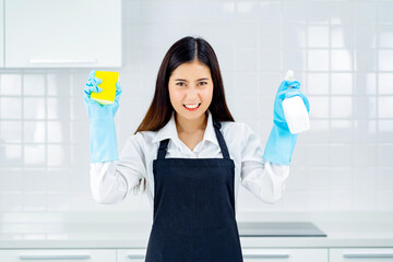 asian woman wearing rubber protective blue gloves standing cleaning with products and equipment kitchen cleaner.