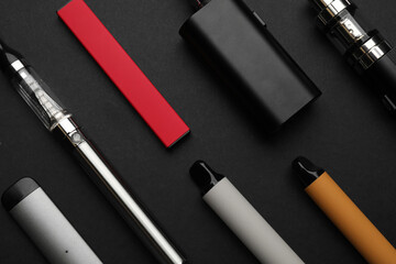 Many electronic smoking devices on black background, flat lay