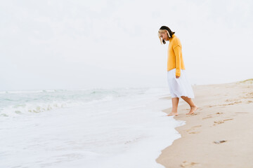 Fototapeta na wymiar Young woman wearing sweater smiling during walking on beach