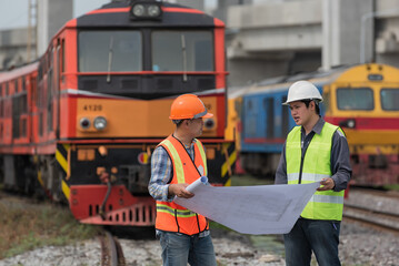 worker and engineer discuss  job  with locomotive on background. railways, engineer, worker, construction