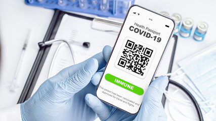 Covid passport doctor holding. Coronavirus vaccination certificate of immunity passport on smartphone screen with doctor stethoscope, syringe and medical equipment on hospital white background.