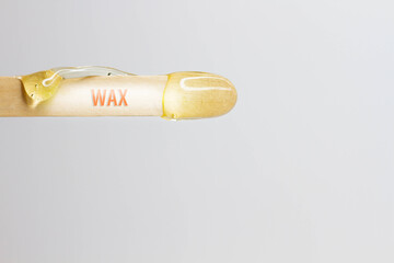 The inscription wax on a wooden spatula with wax for hair removal.