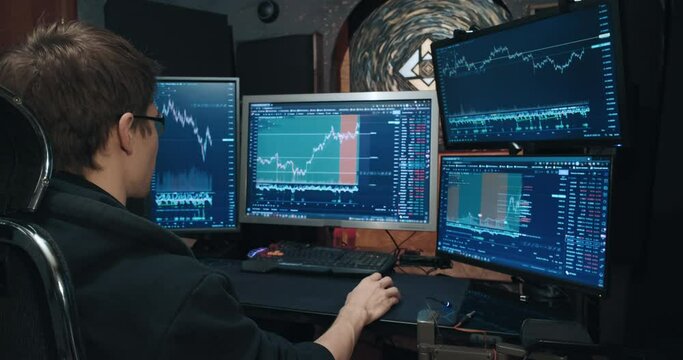 Man trader, freelancer on stock exchange trades options computer, charts of growth and fall of quotations on screen, home environment. Concept of playing on stock, futures and bonds trading exchange