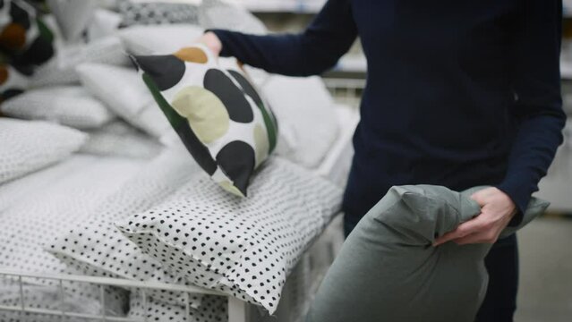 Woman in a home goods store. An unrecognizable person chooses pillows for the interior of his apartment.