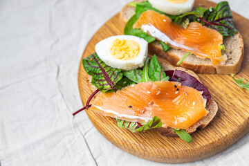 salmon sandwich smorrebrod egg, green salad mix, cereal bread toast seafood open sandwich fresh portion dietary healthy meal food snack on the table copy space food background rustic top view