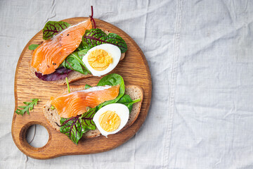 salmon sandwich smorrebrod egg, green salad mix, cereal bread toast seafood open sandwich fresh portion dietary healthy meal food snack on the table copy space food background rustic top view
