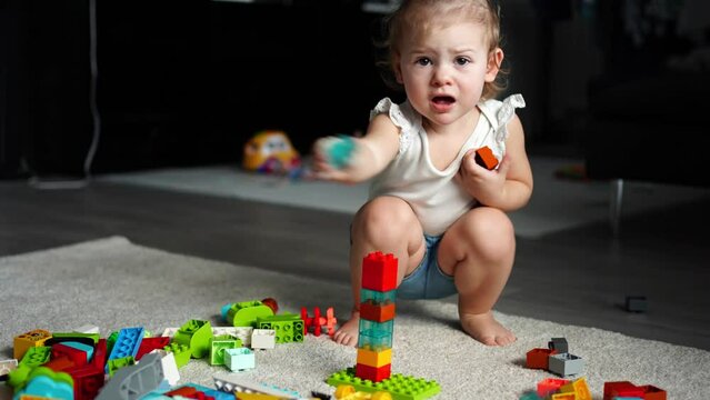 Caucasian child a little girl is playing in the constructor at home. Educational toys for children.