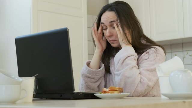 Haggard Caucasian Female Freelancer Working on Laptop in the Kitchen. Lots of Empty Coffee Cups Scattered All Over the Table. Working Overtime, Remote Work and Freelancer Lifestyle Concept